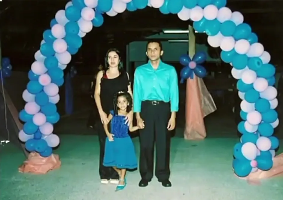 Foto antiga de uma família sob um arco de balões azuis e brancos numa festa da escola