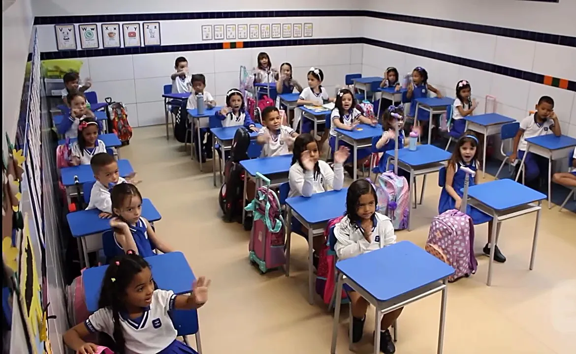 Sala de aula climatizada do Infantil, com carteiras azuis e alunos de uniforme no primeiro dia de aula