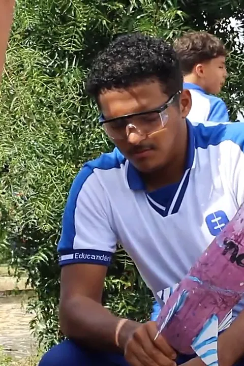 Aluno do Ensino Médio de óculos de proteção preparando um foguete ao ar livre